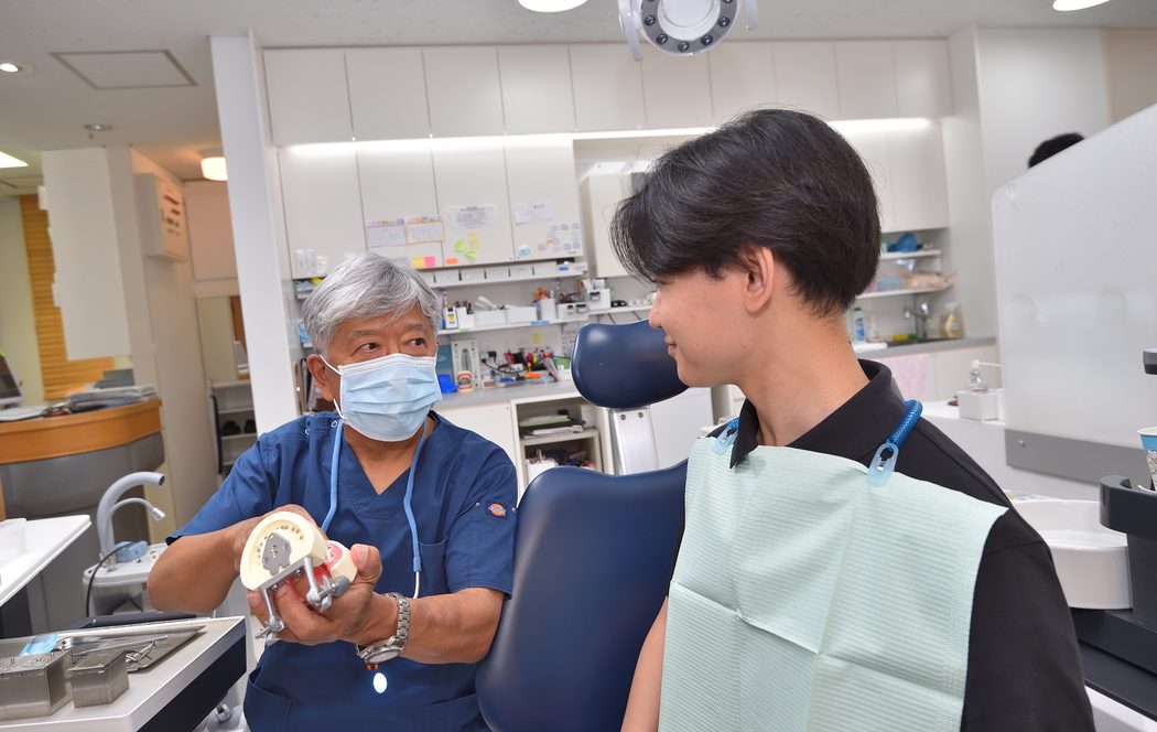 歯の模型を持って説明する院長と患者