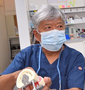 患者に入れ歯の模型を見せる院長