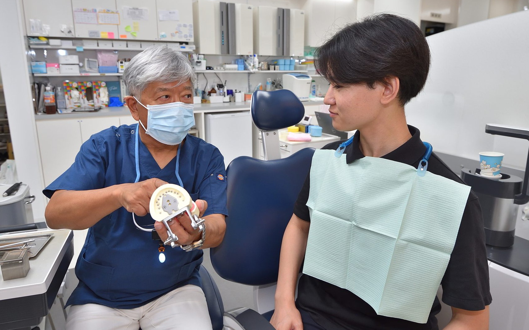 入れ歯の模型を持って説明する院長