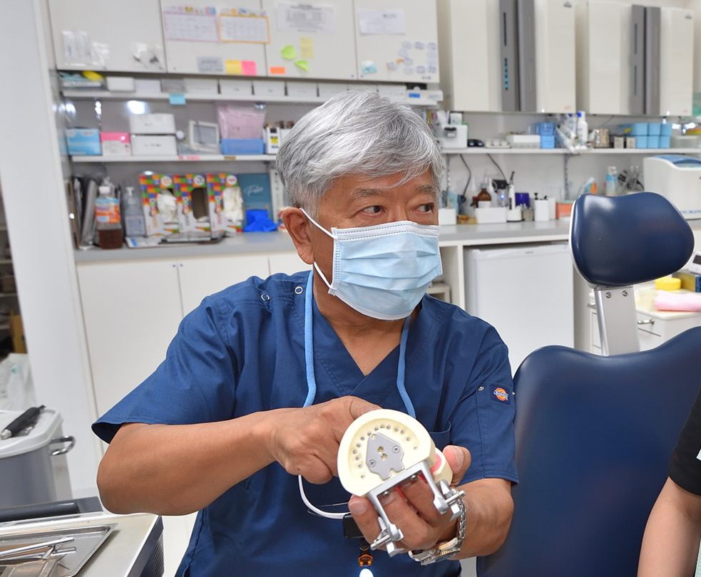 入れ歯の模型を持って説明する院長