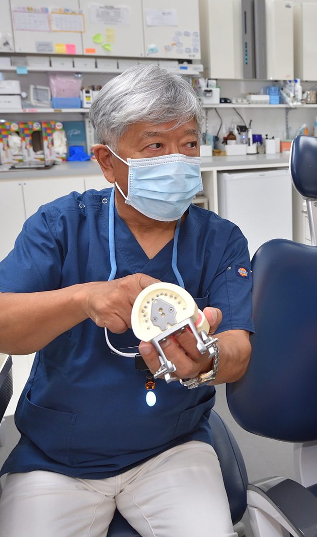 入れ歯の模型を持って説明する院長