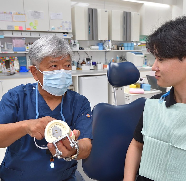 入れ歯の模型を持って説明する院長