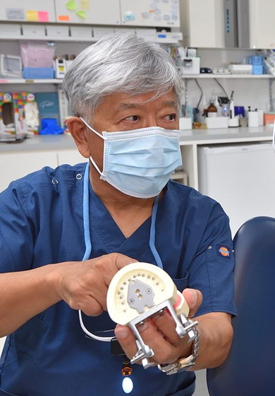 入れ歯の模型を持って説明する院長